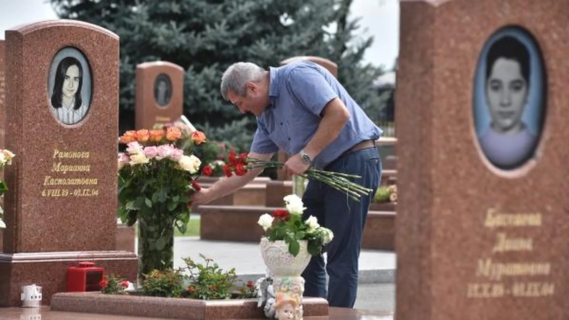 Мужчина принес цветы на могилу на мемориальном кладбище «Город ангелов» в Беслане