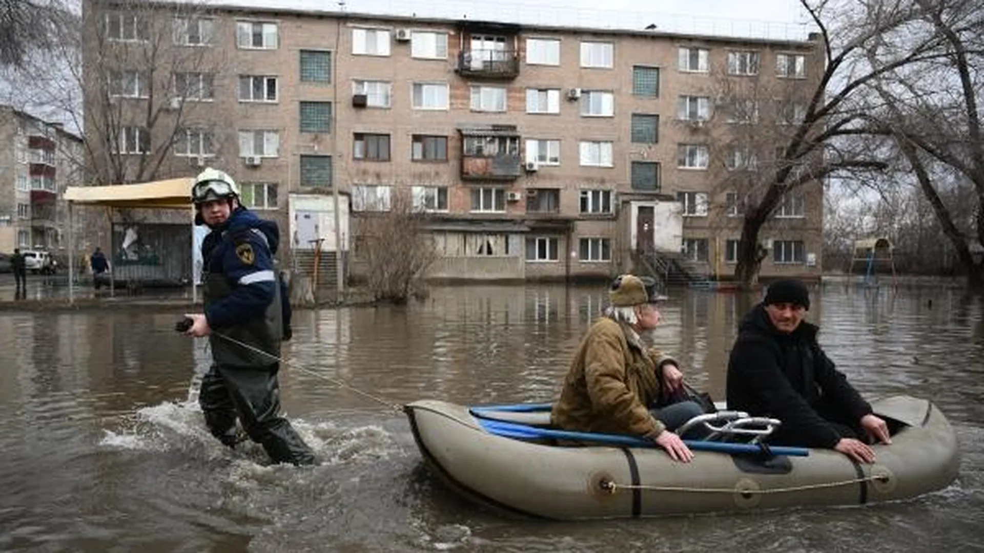 Сотрудник МЧС эвакуирует жителей затопленного из-а прорыва дамбы района Орска