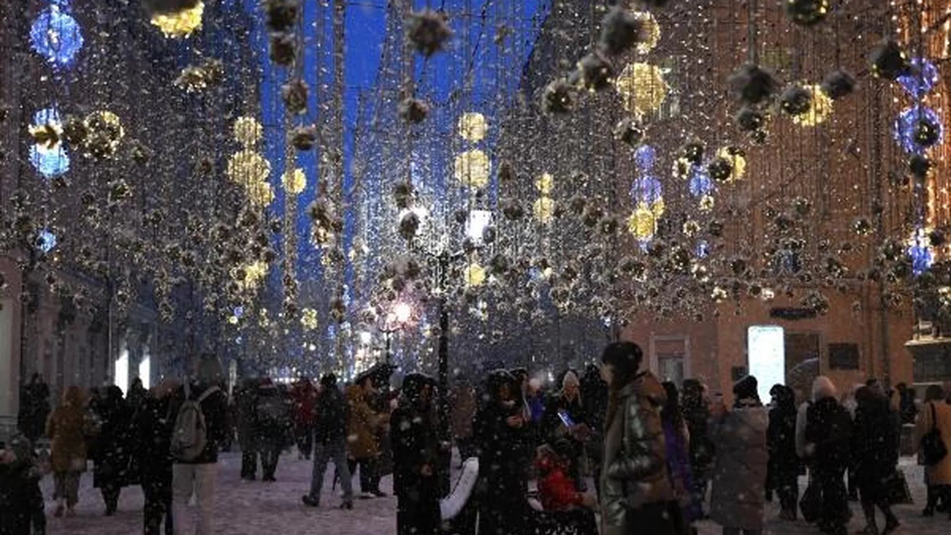 Люди на Никольской улице в Москве, украшенной к Новому году