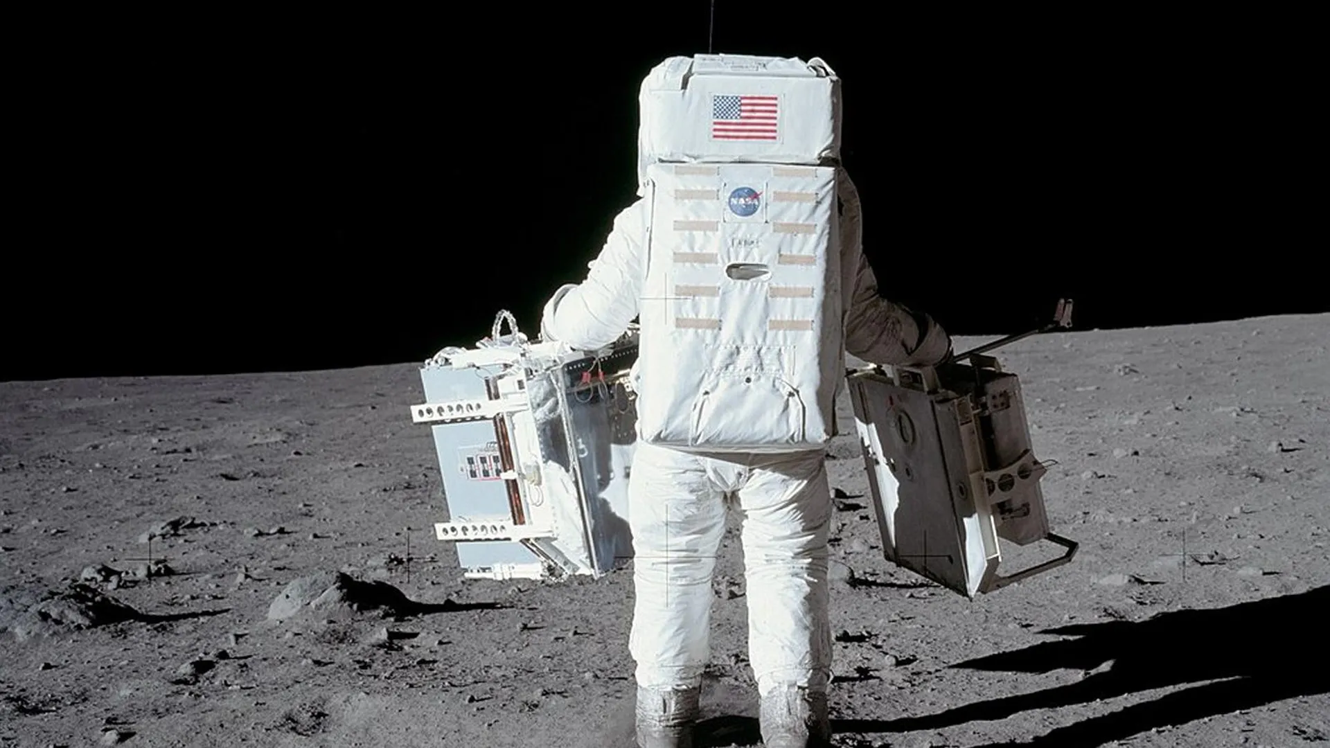 Астронавт Базз Олдрин переносит на Луне комплект научных приборов