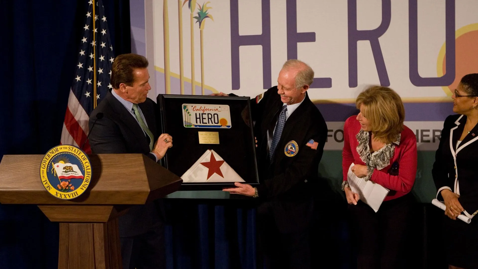Губернатор Калифорнии Арнольд Шварценеггер вручает Чесли Салленбергу автономера с надписью «Герой» и флаг штата