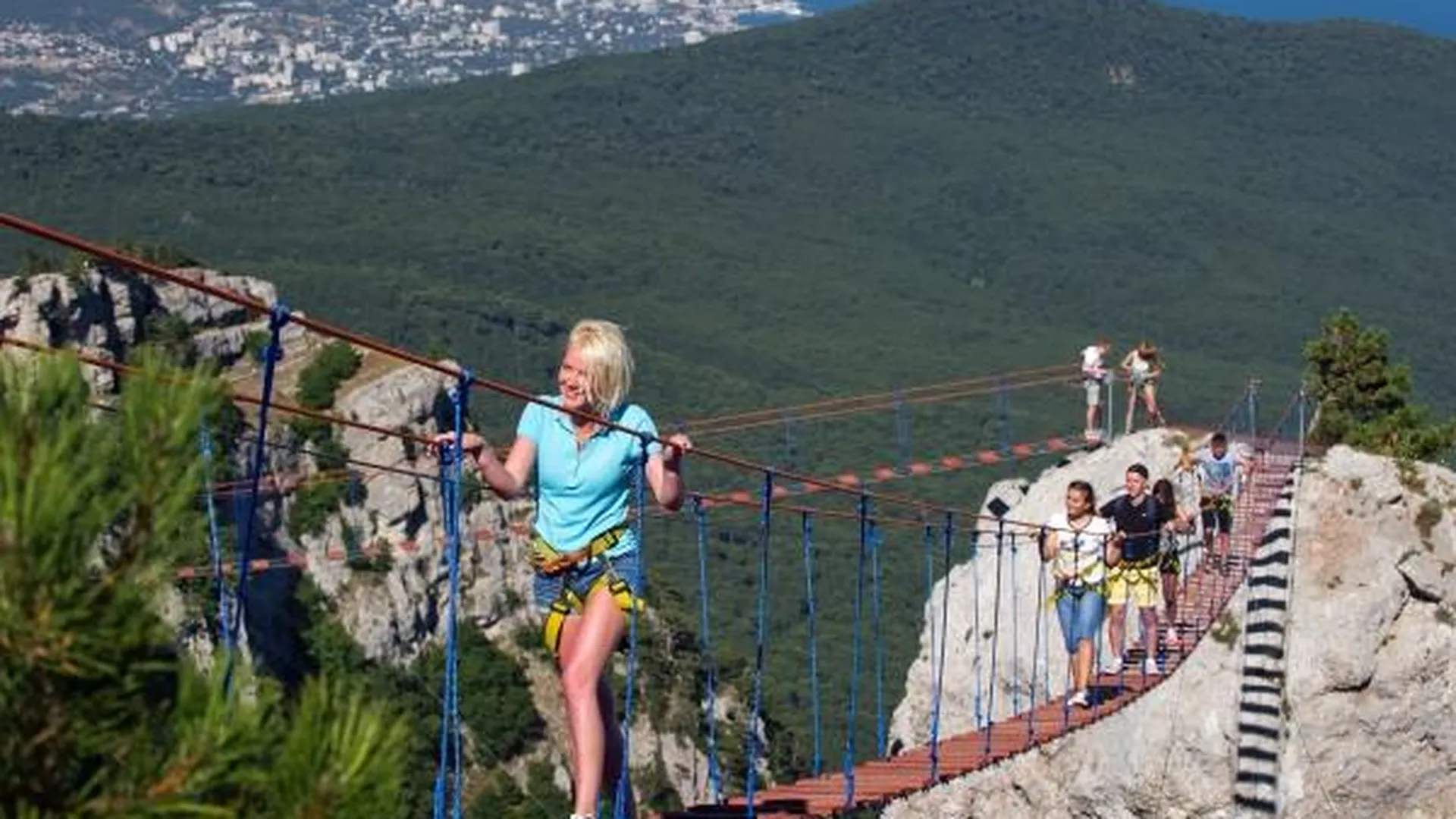 Туристы идут по веревочной лестнице между зубцами горы Ай-Петри в Крыму