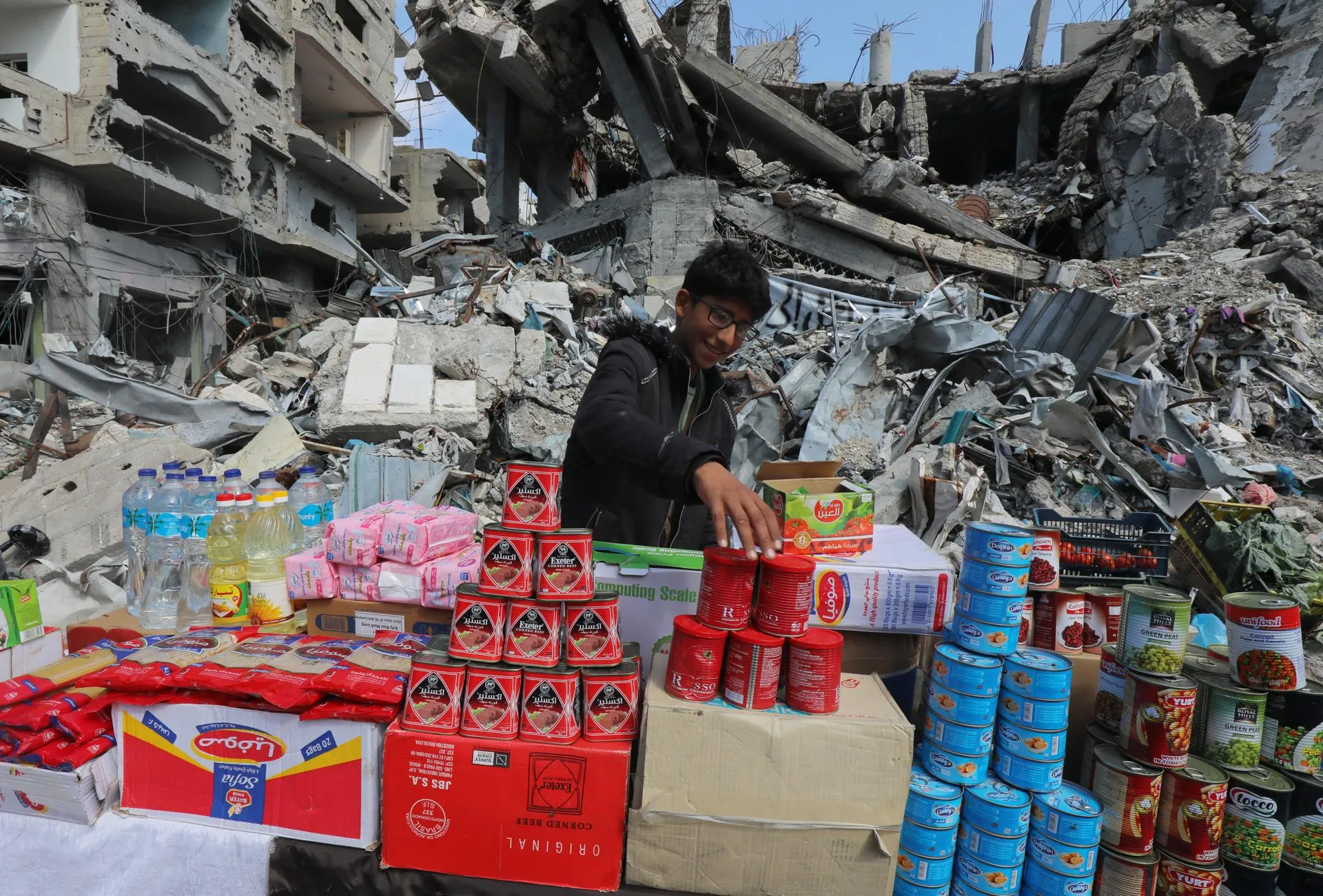 Подросток торгует на стихийном рынке у разрушенных зданий. Лагерь беженцев Нусейрат, Газа