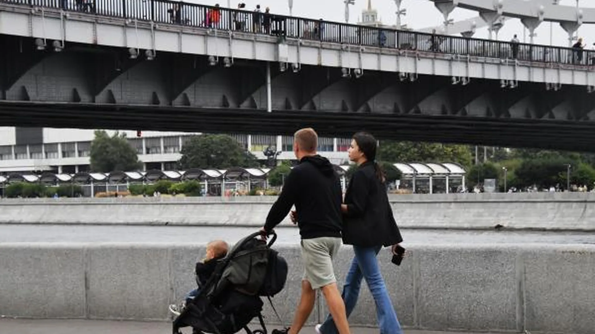 Пара с детской коляской гуляет по набережной