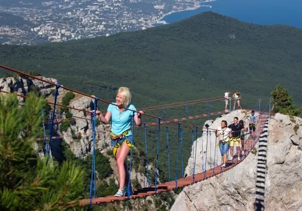 Туристы идут по веревочной лестнице между зубцами горы Ай-Петри в Крыму