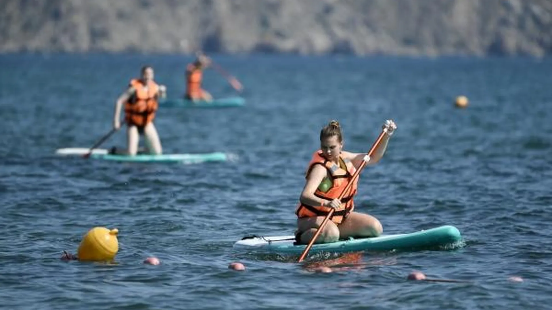 Отдыхающие плавают на доске для саб-серфинга на праздновании Дня молодежи в бухте Капсель