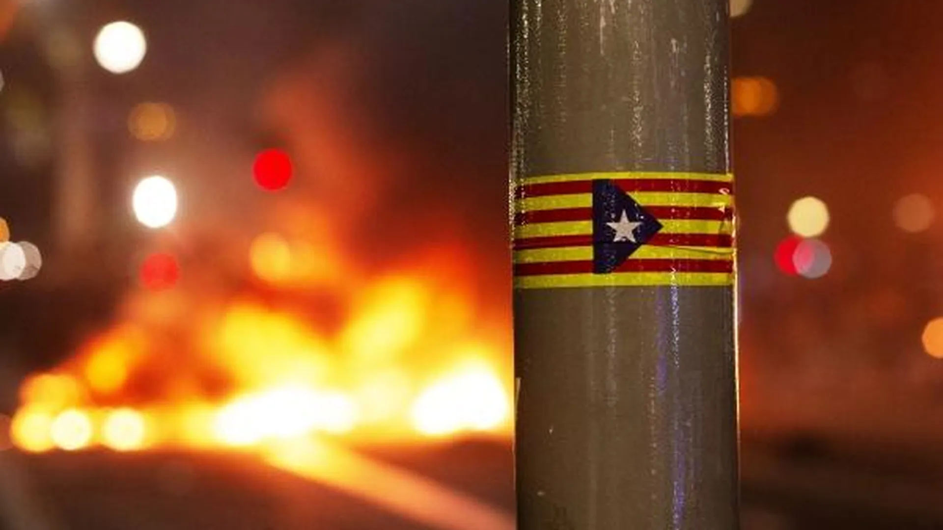 Наклейка с изображением флага Каталонии на фонарном столбе во время беспорядков, возникших в ходе акции протеста в Барселоне