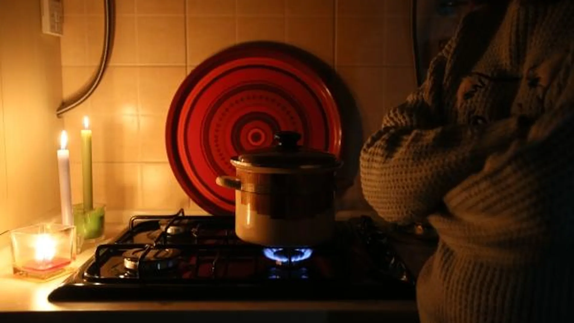 Девушка разогревает суп на газовой плите во время тестового отключения электричества в Киеве