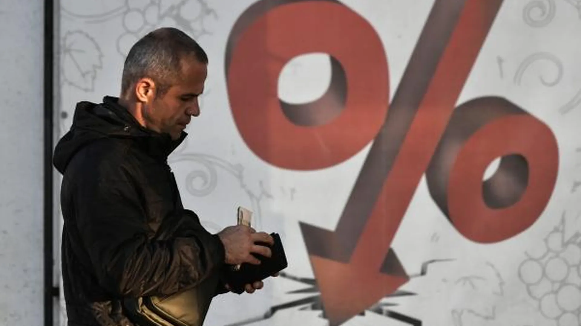 Мужчина проходит мимо плаката с изображением процентов на одной из улиц в Симферополе.