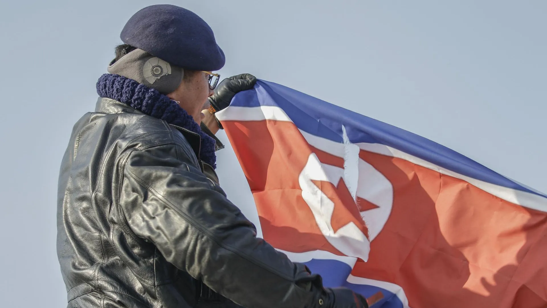Протестующий держит сорванный флаг Северной Кореи на мосту Объединения возле Пханмунджома в Паджу, Южная Корея, 2018 год. Пханмунджом — это место, включающее в себя здания для проведения переговоров по вопросам, касающимся двух стран Корейского полуострова в демилитаризованной зоне. Фото: Ryu Seung-Il / ZUMAPRESS.com